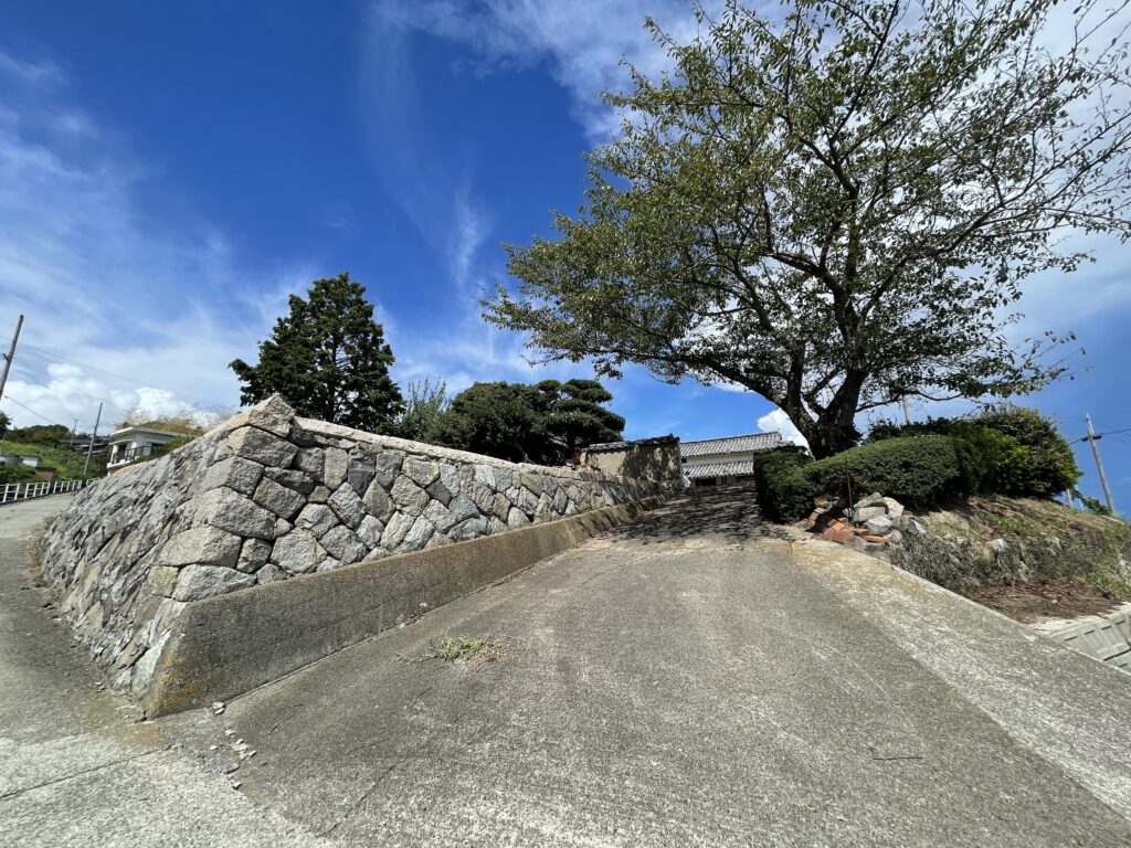 石垣に沿ったアプローチ。上がった先が敷地です