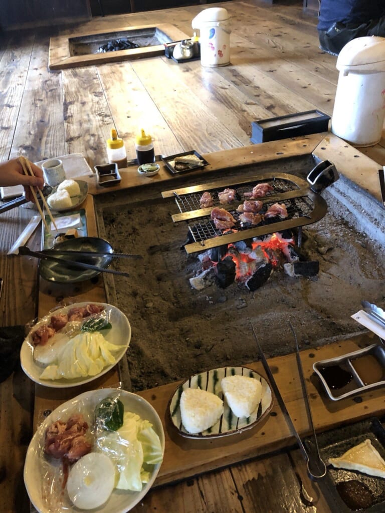 高森田楽の里で。囲炉裏の炭火で、地鶏を自分で焼きながらいただきます。奥にも囲炉裏が並んでいます